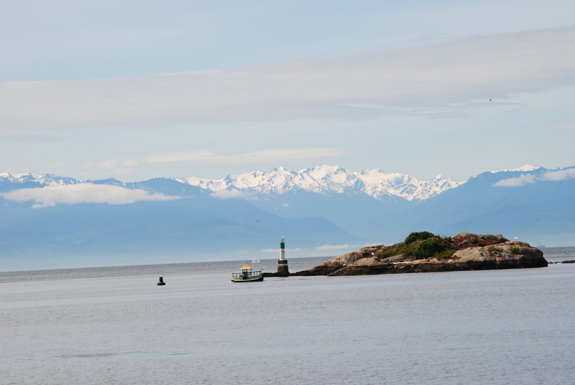 A small island in the middle of the ocean with mountains in the background.