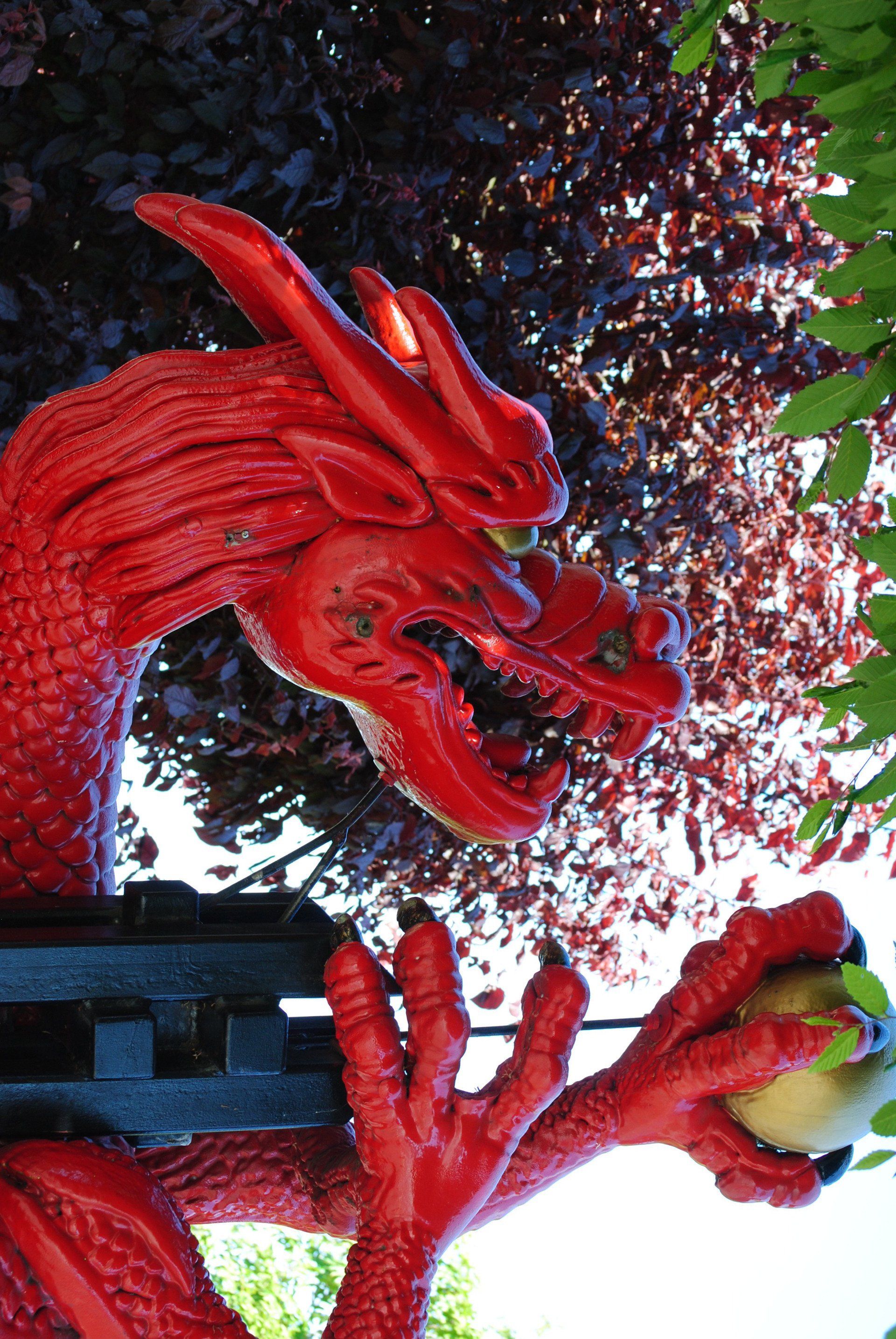 A statue of a red dragon holding an apple