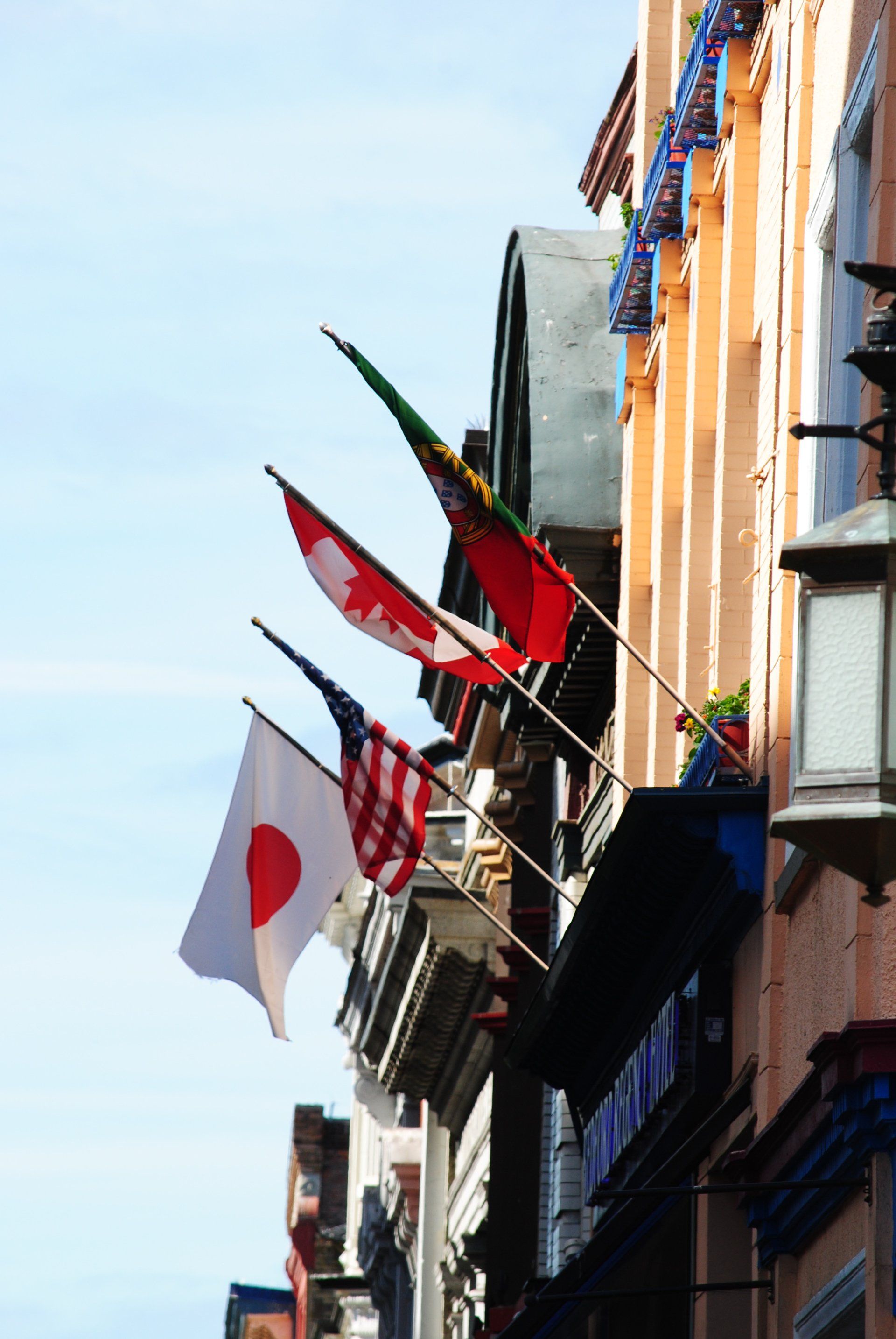 A row of flags are hanging from the side of a building