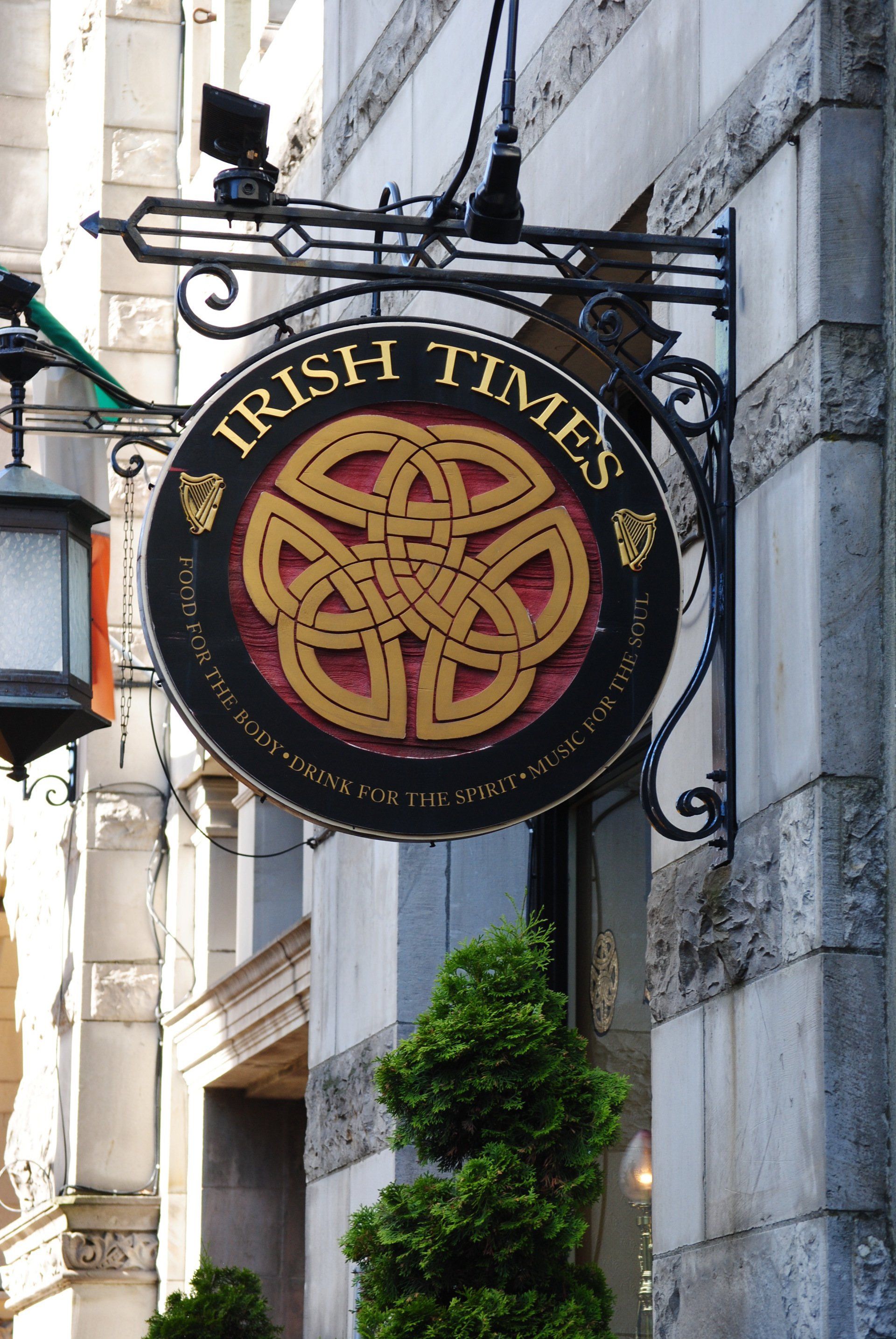 A sign for irish times hangs from the side of a building
