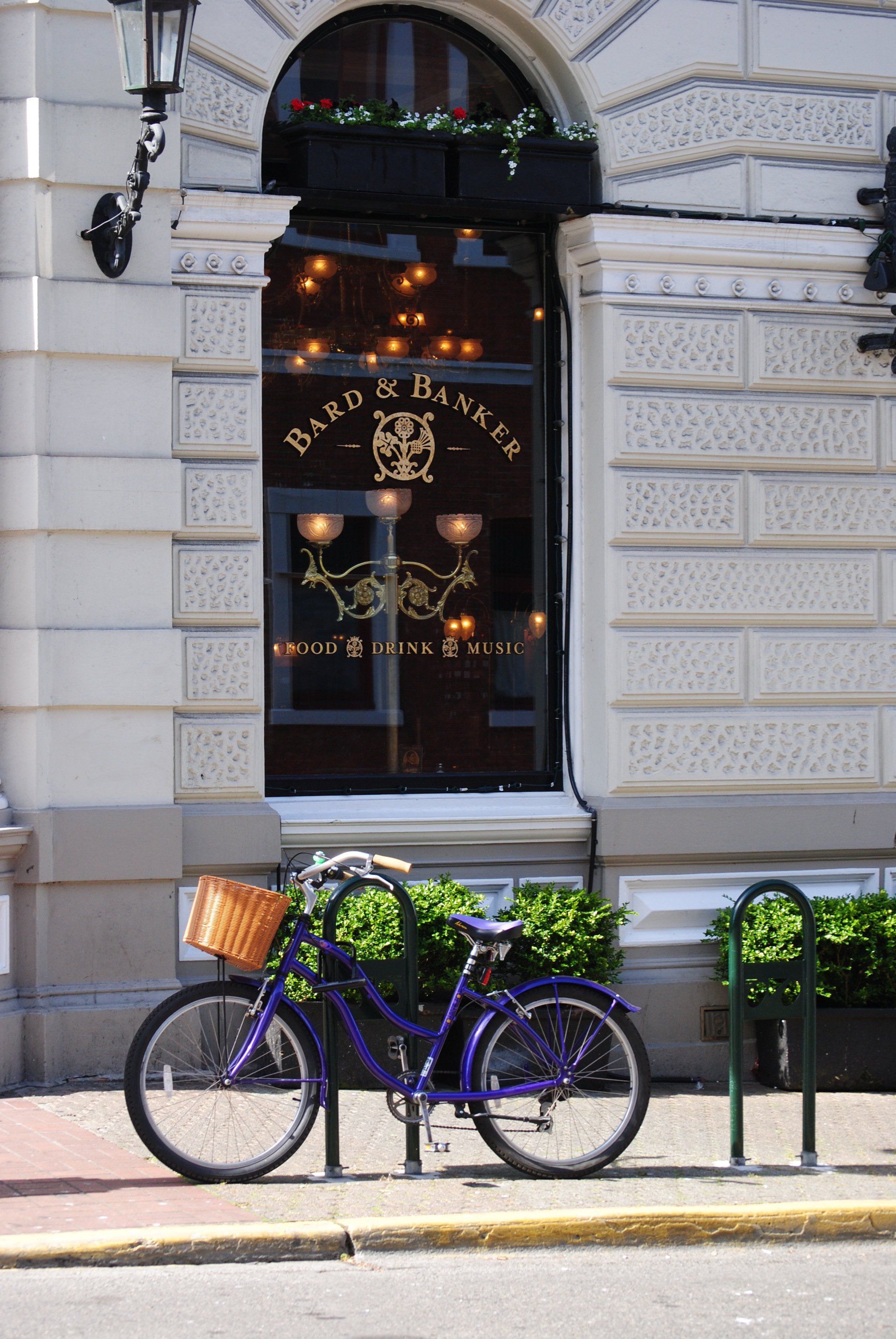 A purple bicycle is parked on the side of the road in front of a building