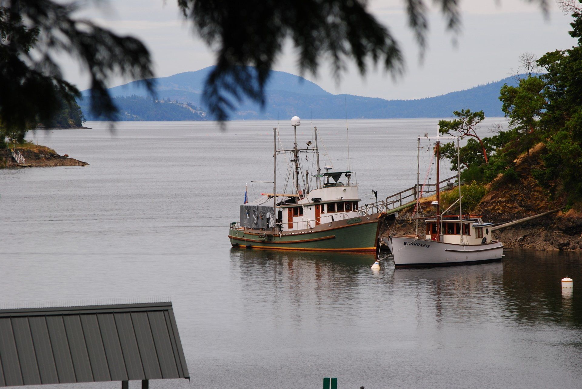 Two boats are docked in a body of water with mountains in the background