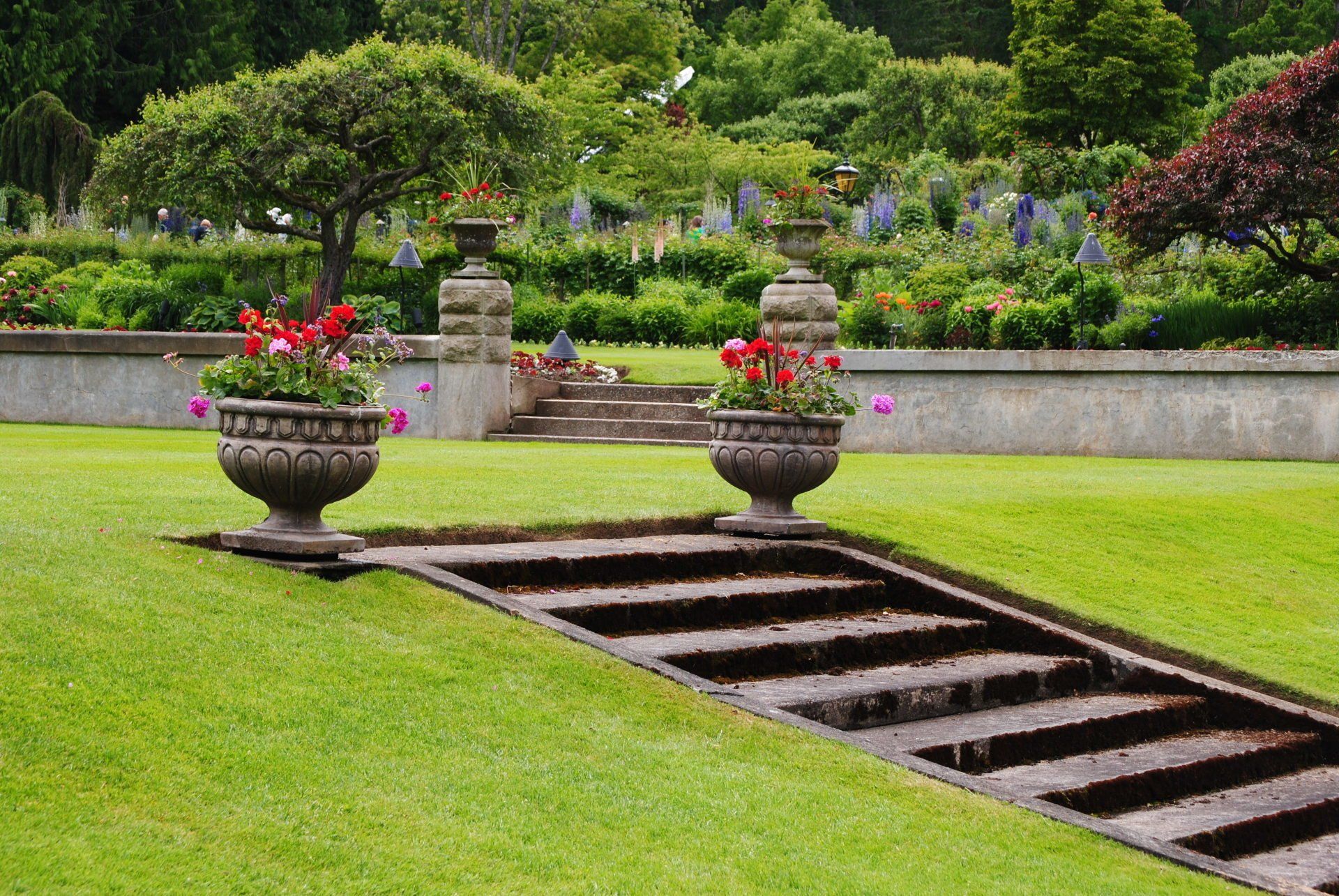 A garden with a staircase and two planters with flowers in them
