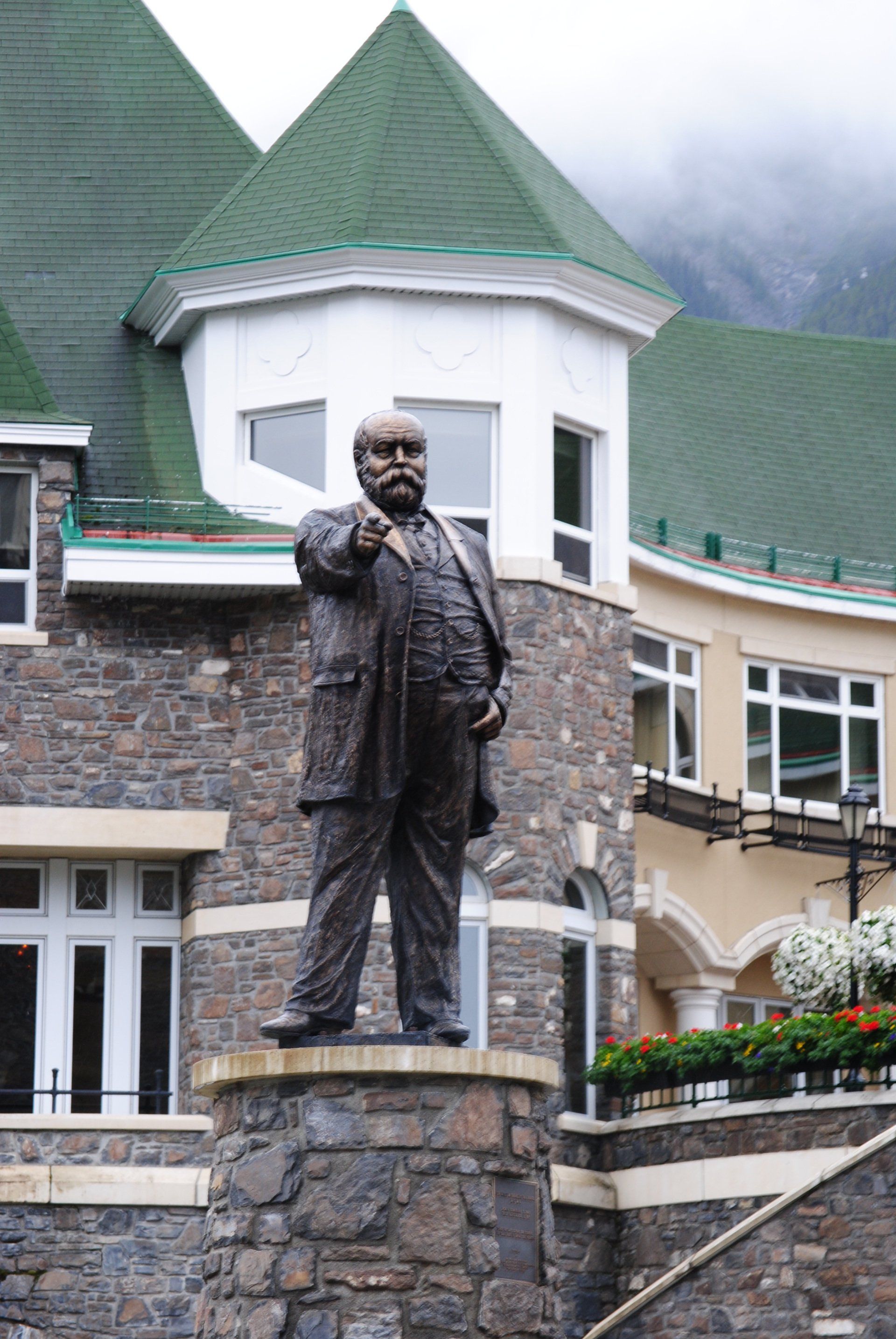 A statue of a man with a beard is standing in front of a building.