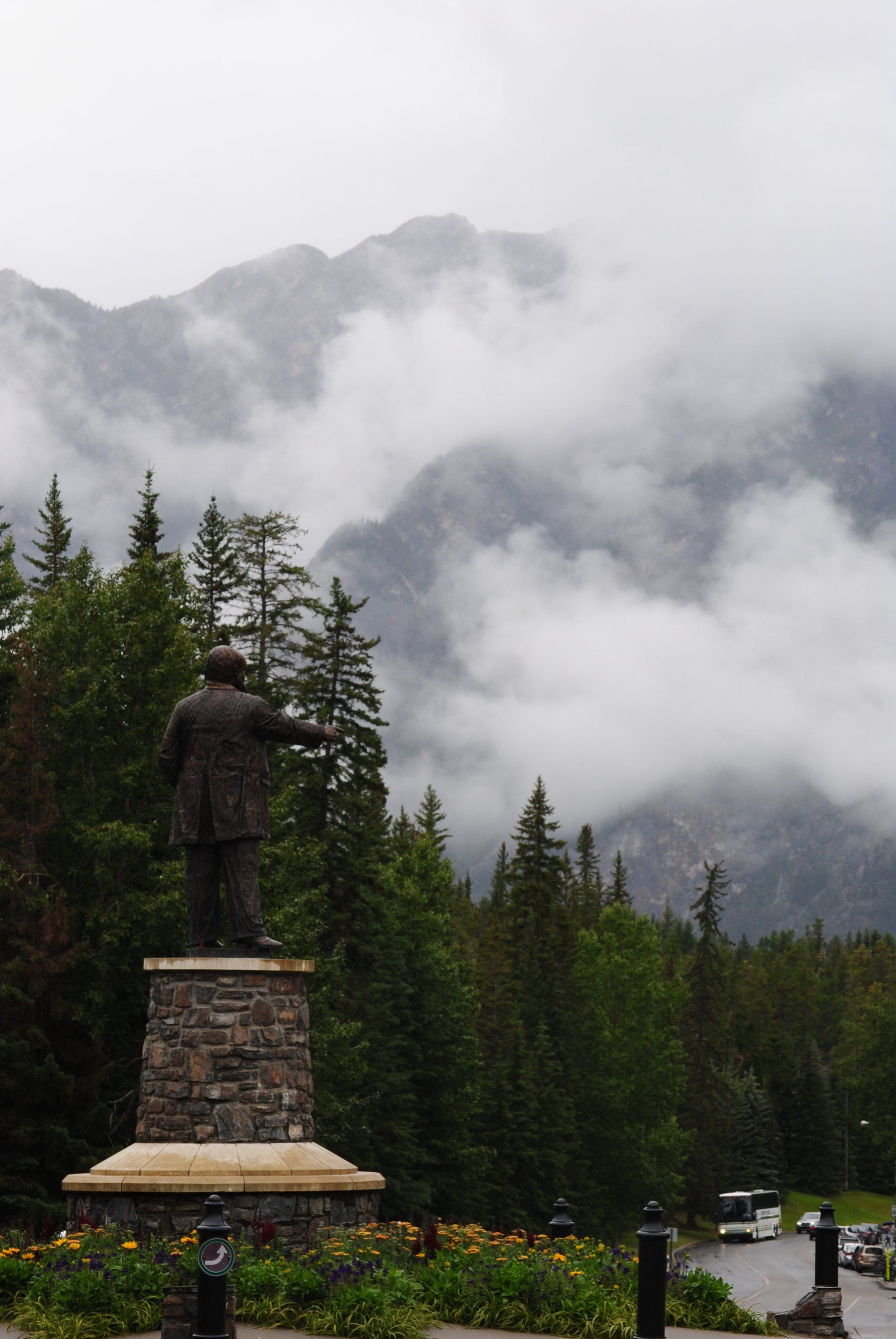 A statue of a man standing in front of a mountain in the fog