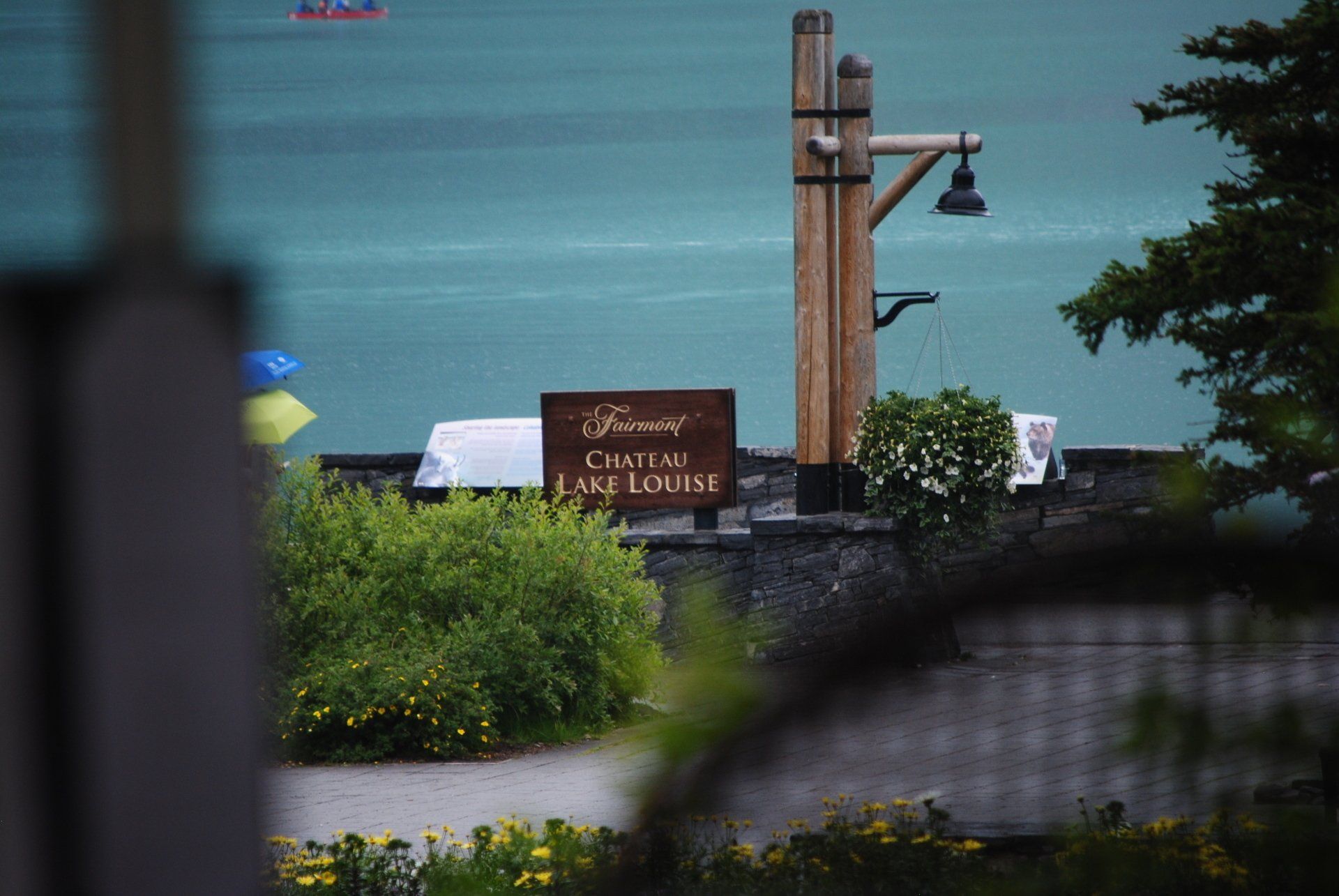 A sign that says ' chateau les louise ' on it is in front of a body of water.
