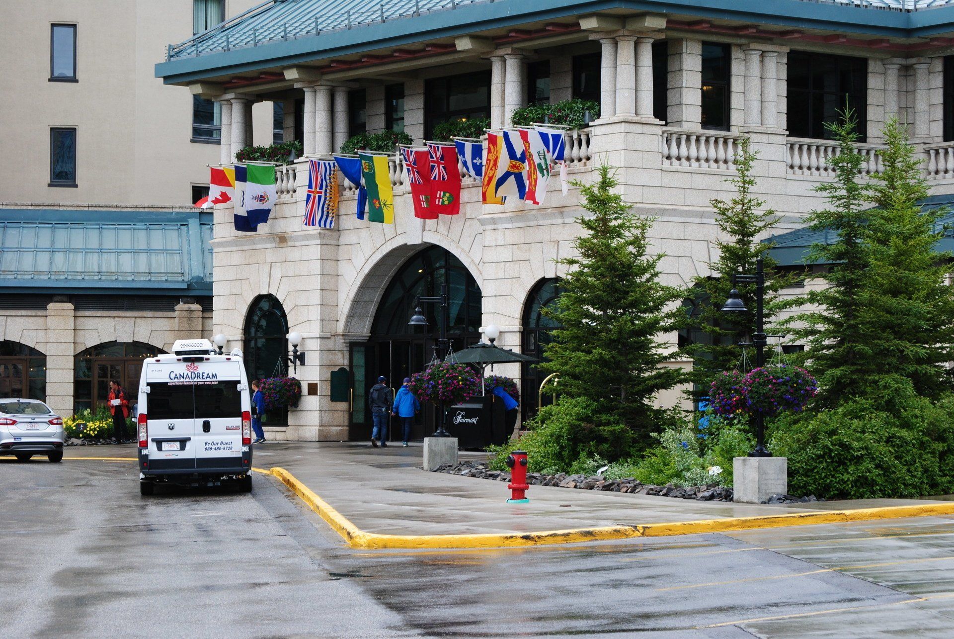 A white van is parked in front of a large building