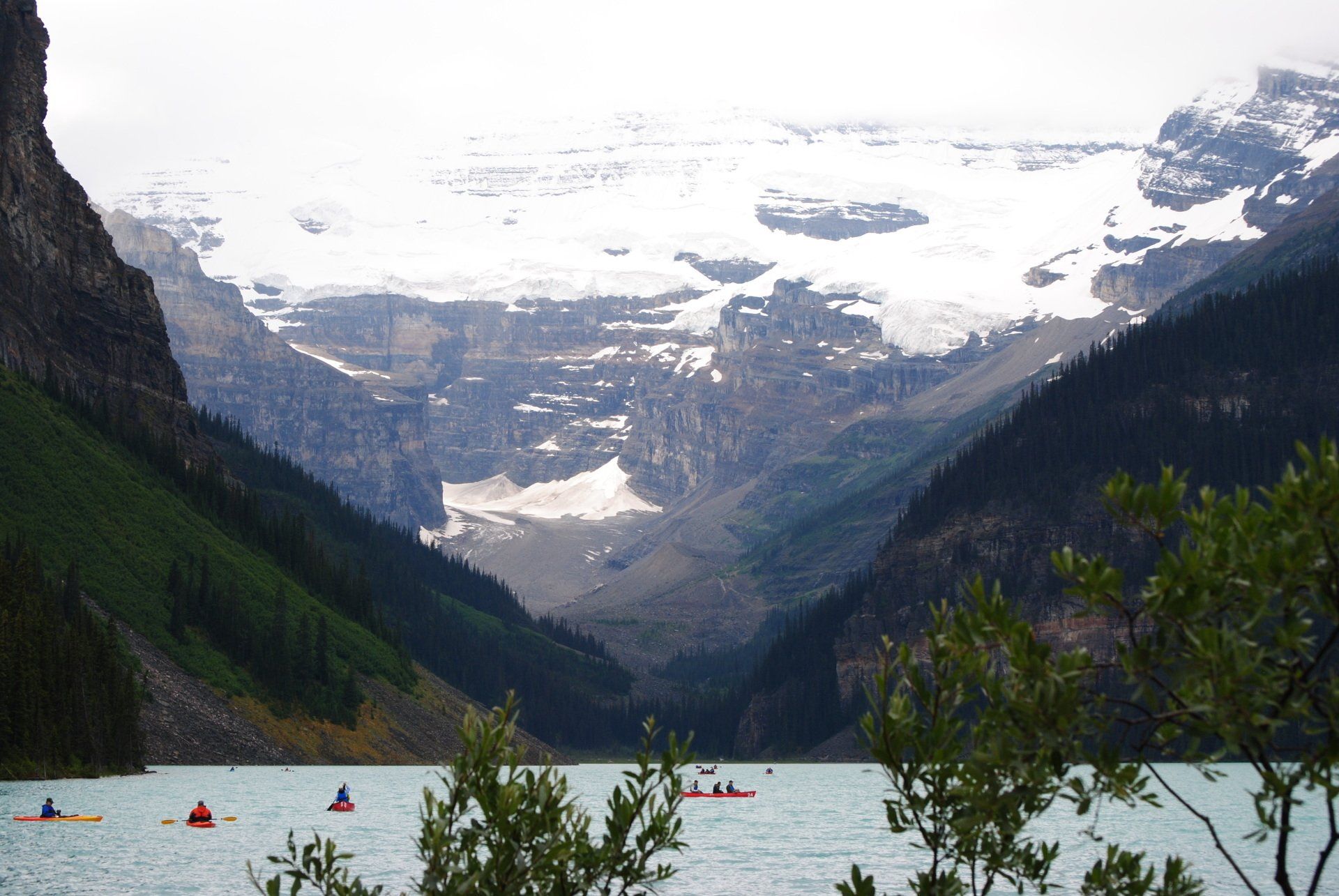 A lake surrounded by mountains and trees with kayaks in the water