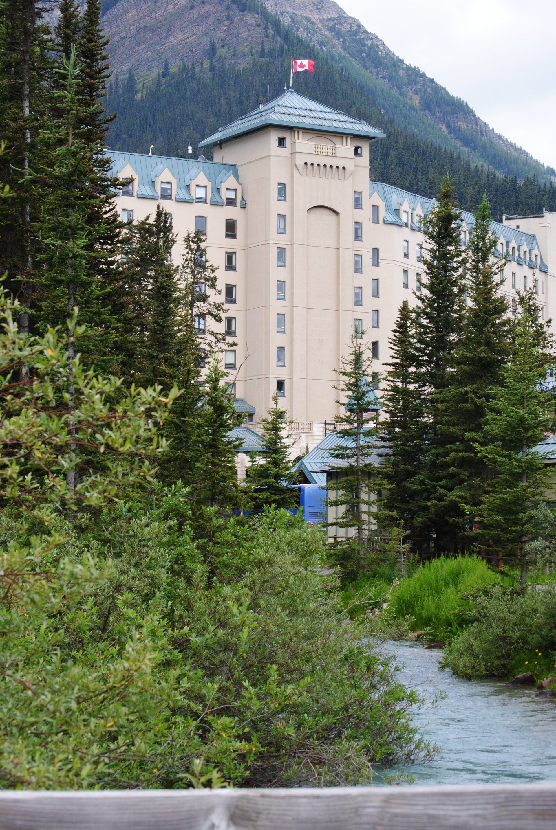 A large building is surrounded by trees and a river.