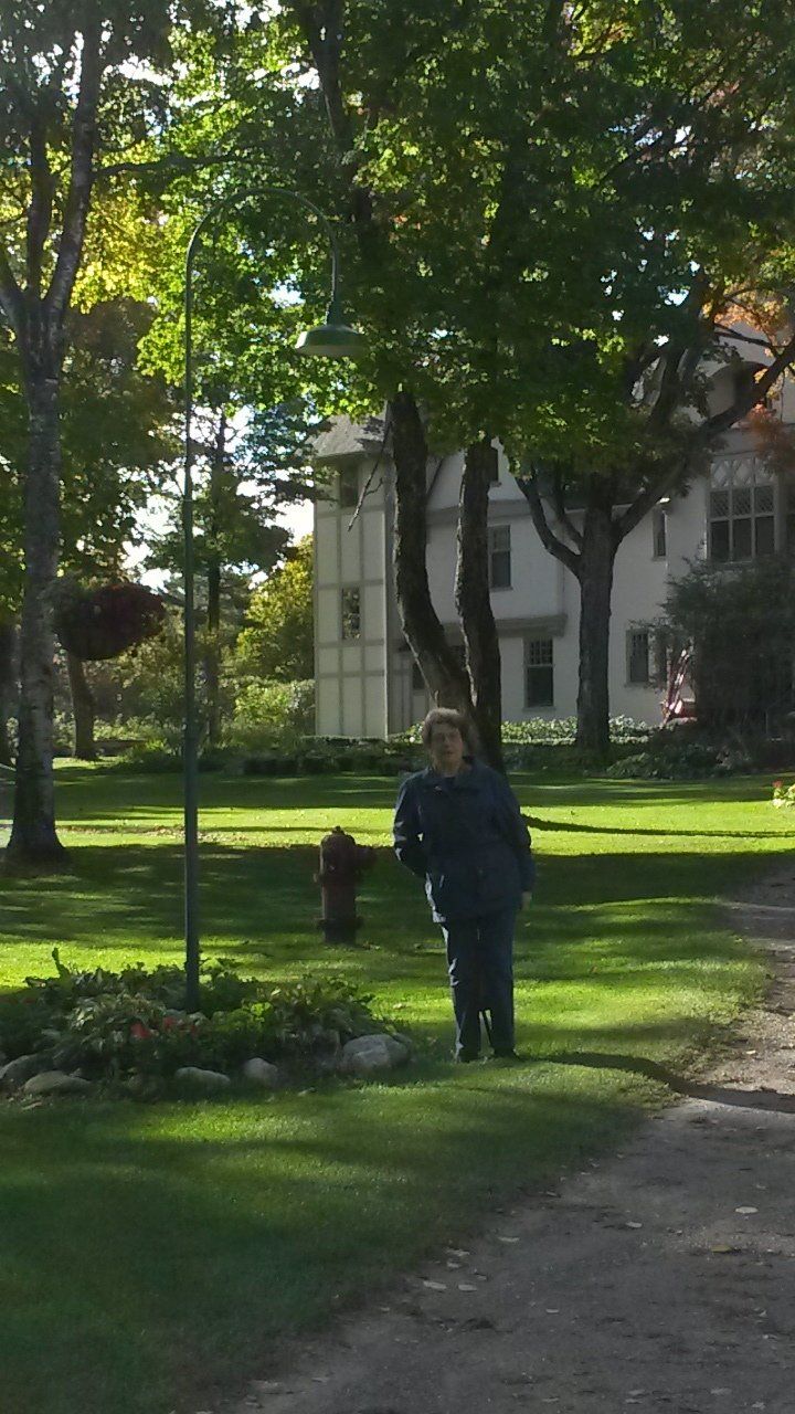 A person standing in a park with a house in the background