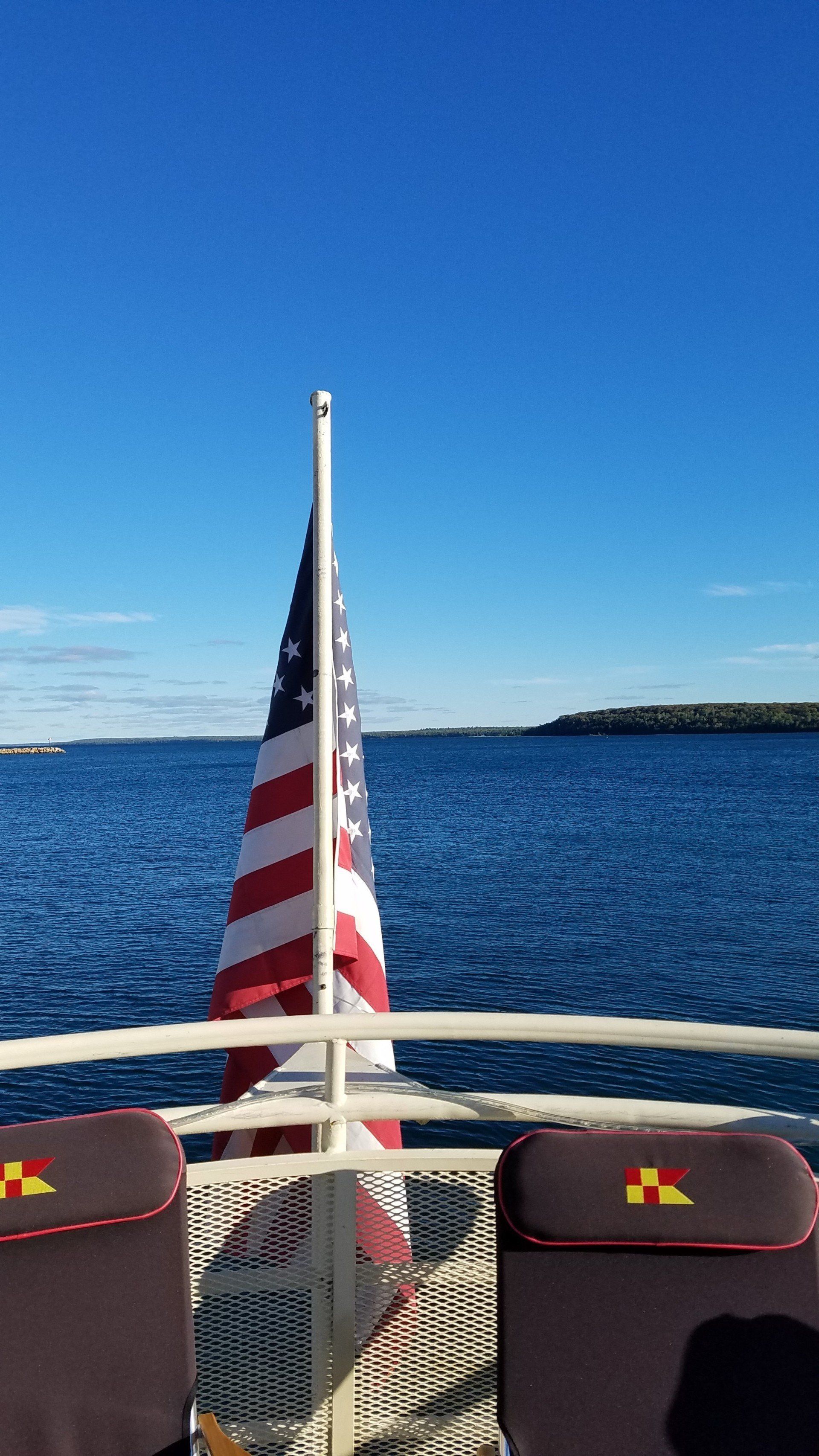 An american flag is flying on the back of a boat.