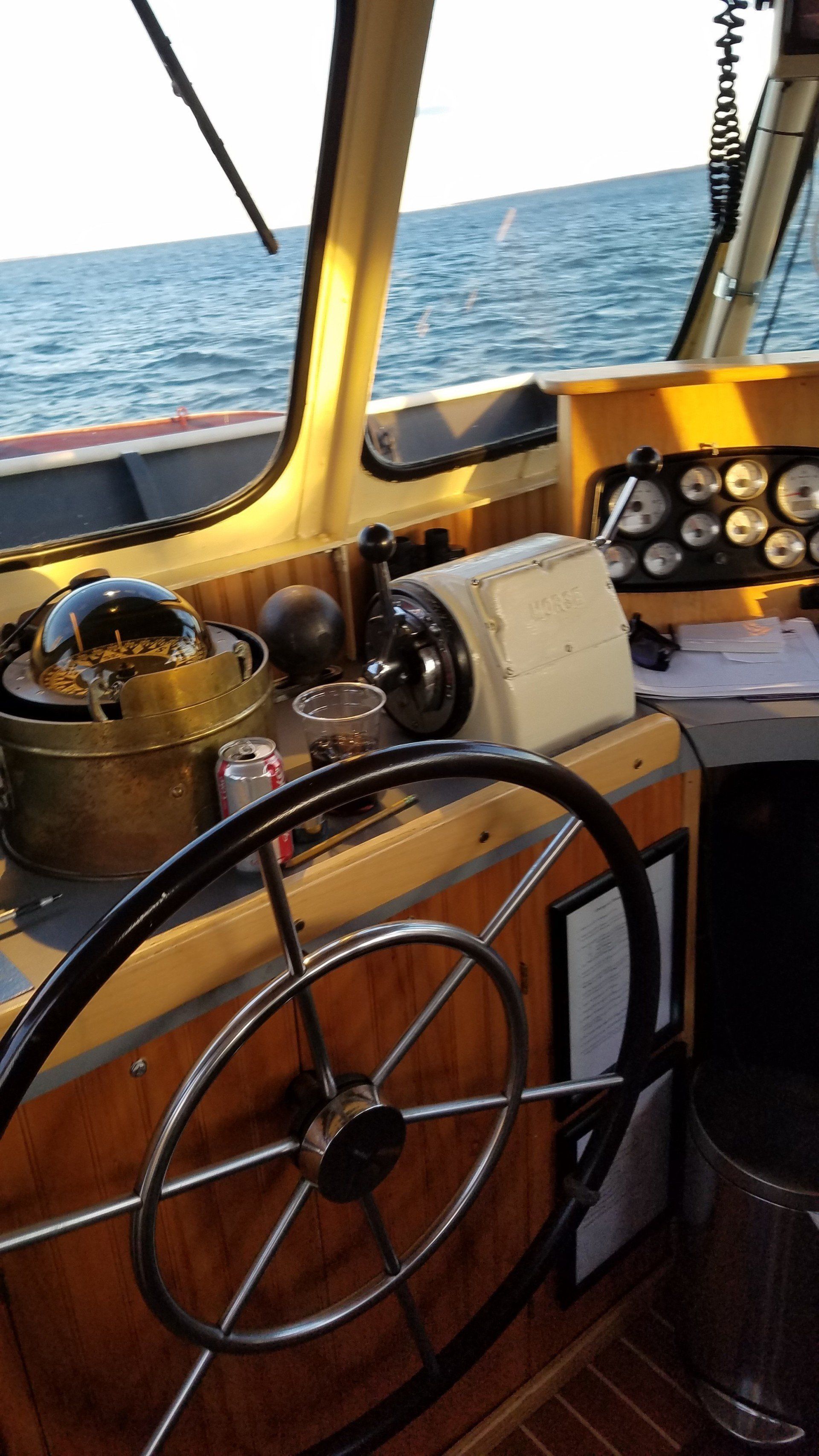 A steering wheel is sitting on a wooden table on a boat.