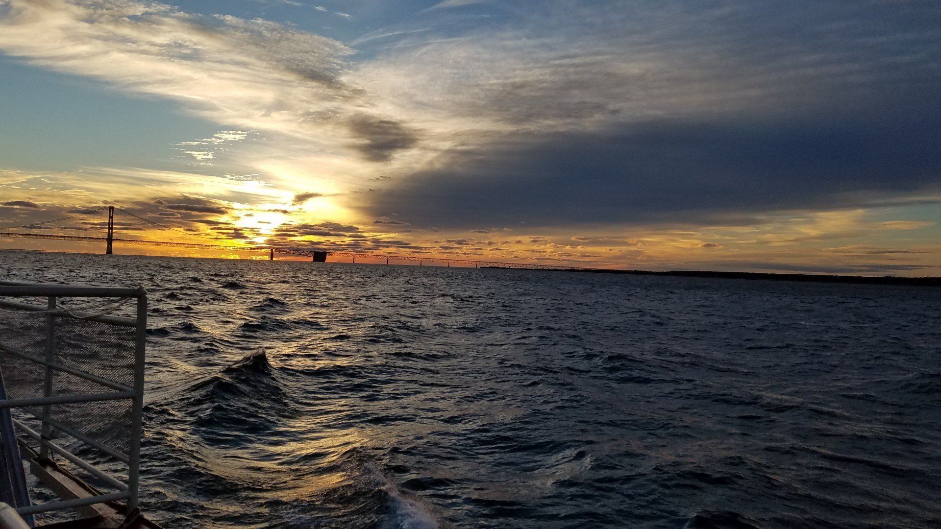 A boat is floating on top of a body of water at sunset.