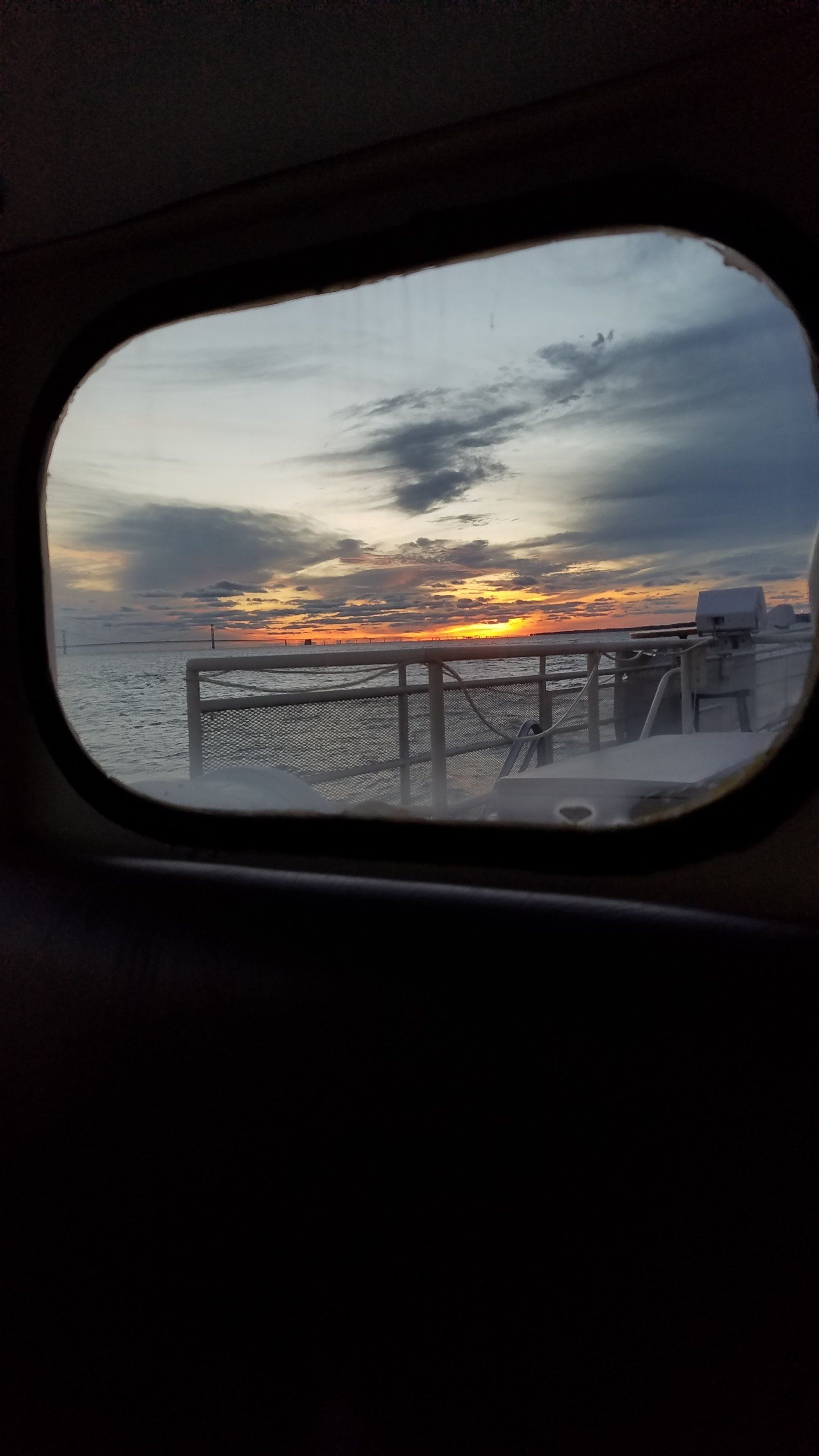 A view of a sunset over the ocean from a car window.