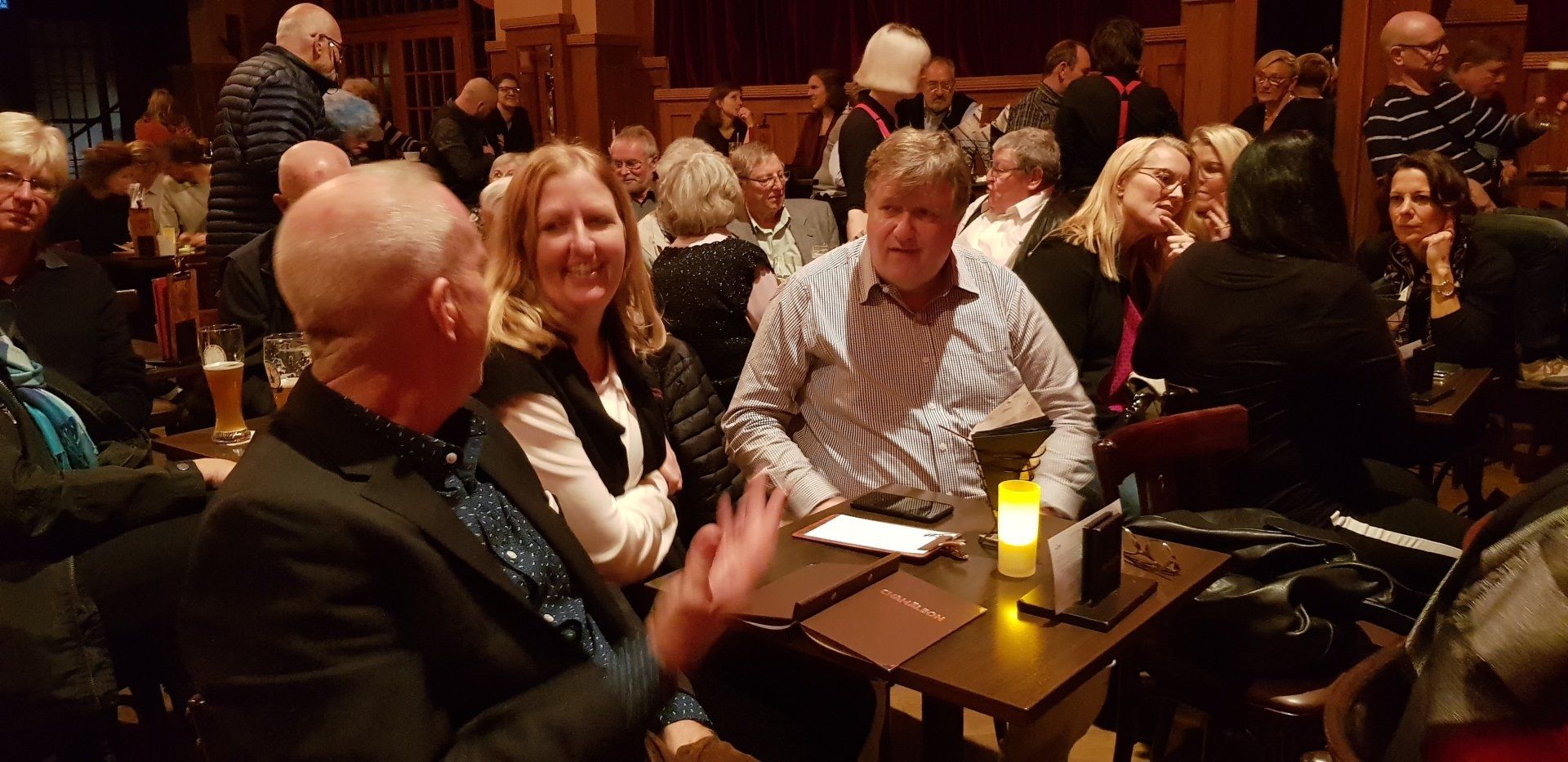 A group of people are sitting at tables in a dark room.