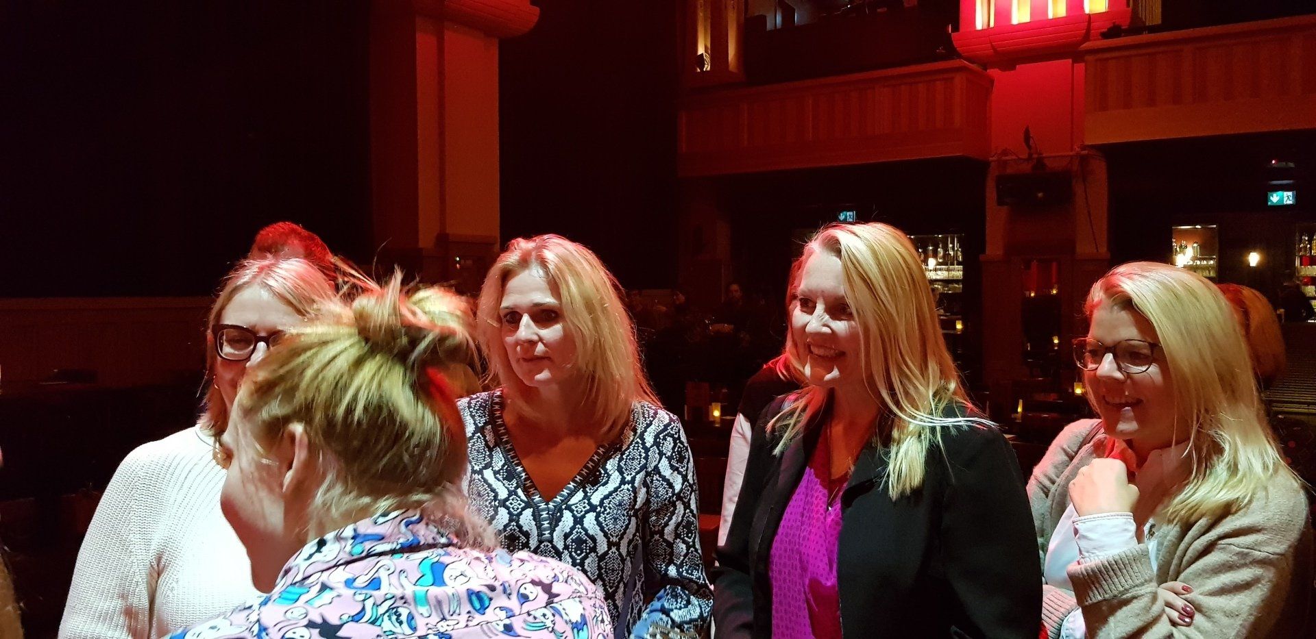 A group of women are standing next to each other in a dark room.