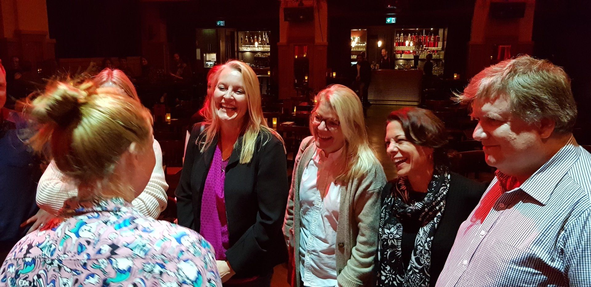 A group of people are standing next to each other in a dark room.