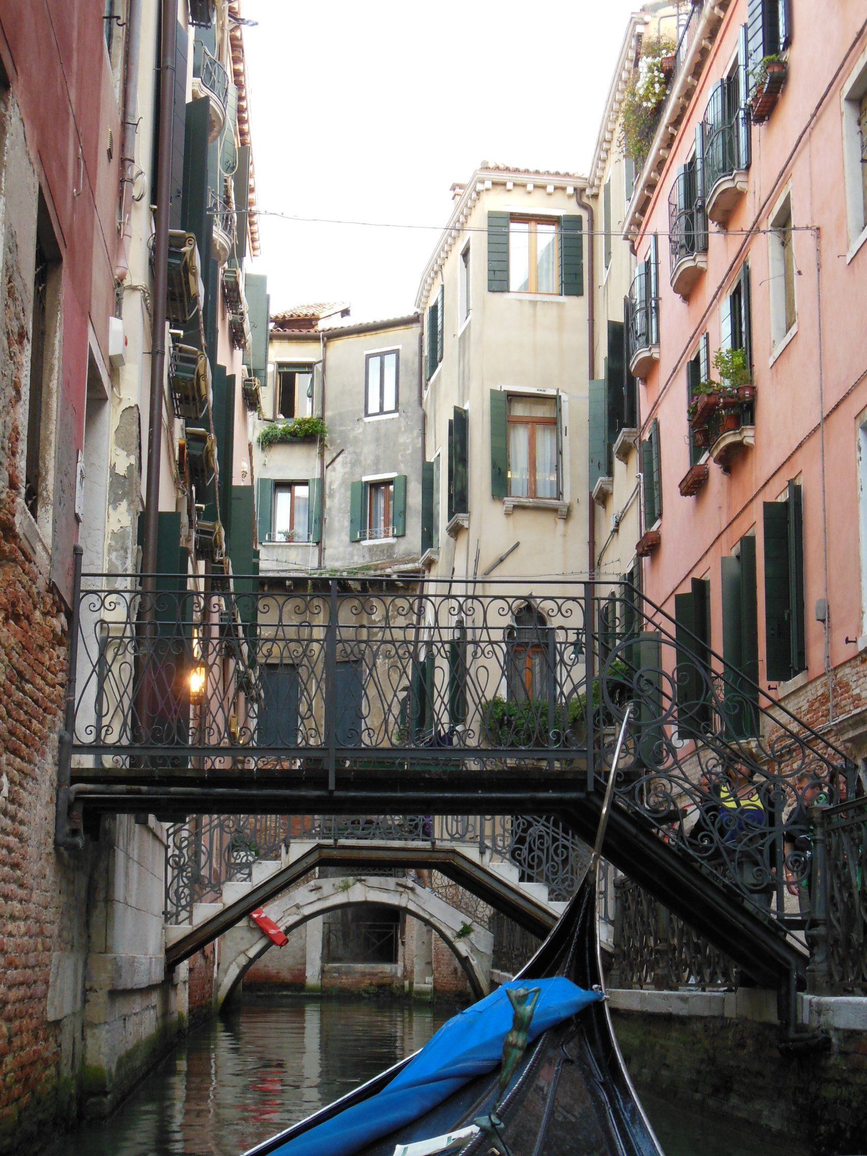 A boat is going under a bridge in a narrow canal