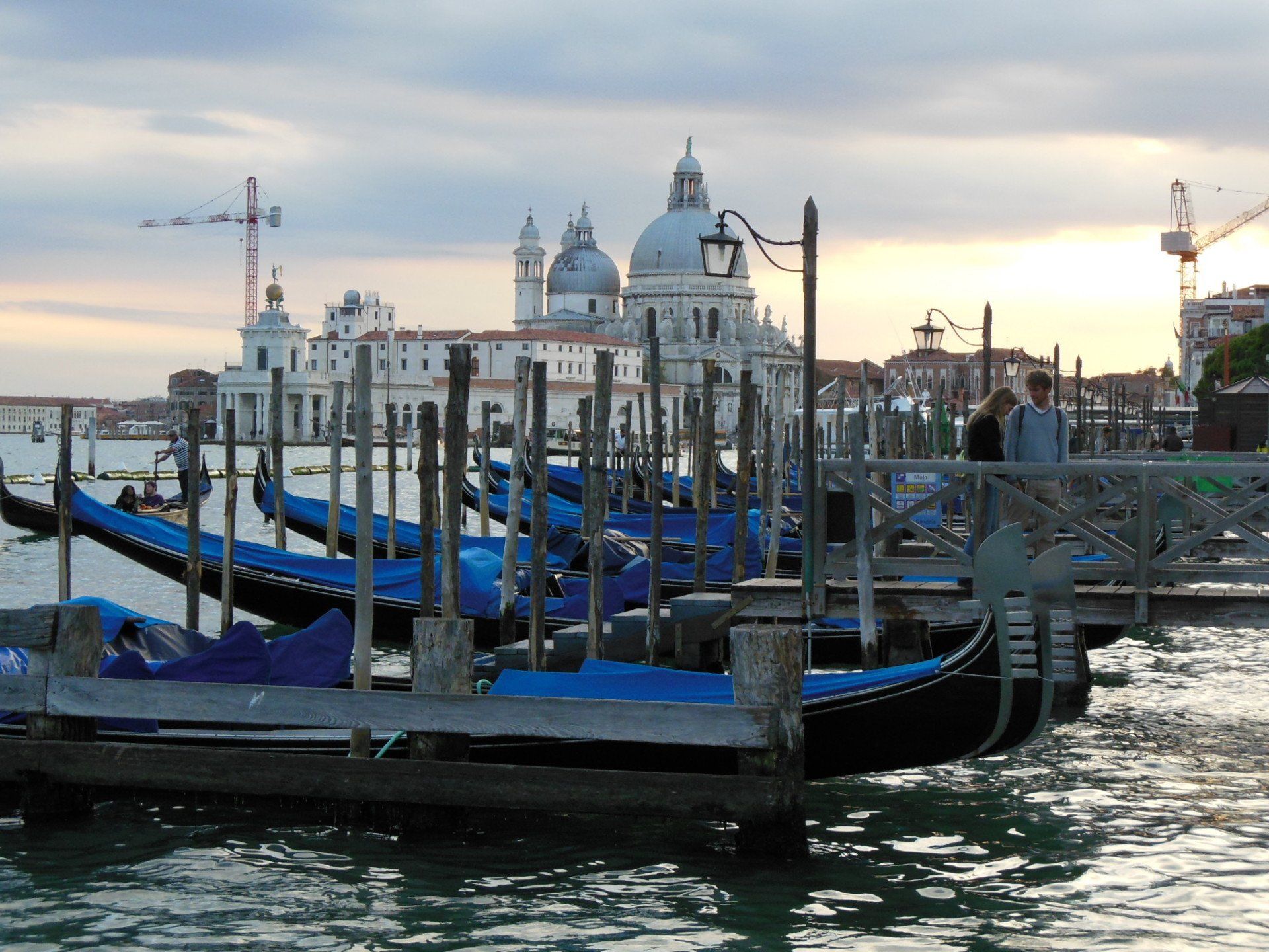 A row of gondolas are docked in front of a large building