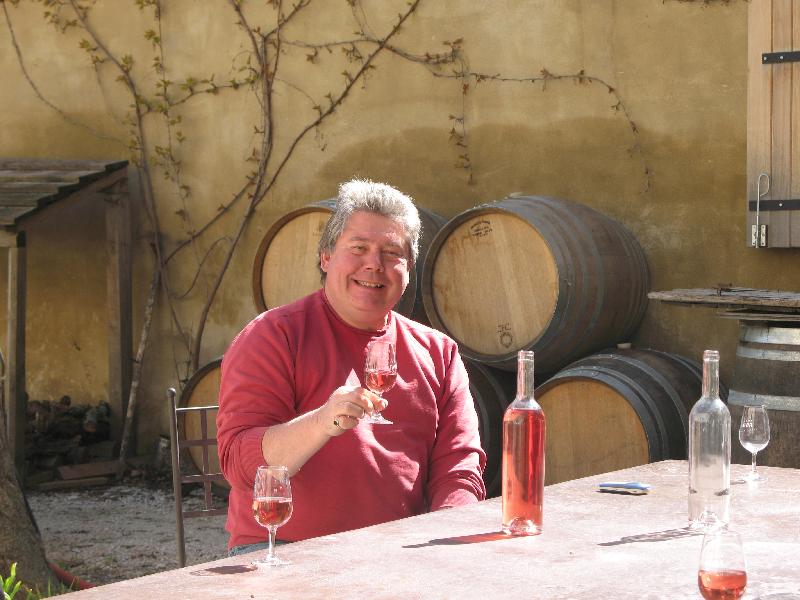 A man is sitting at a table holding a glass of wine