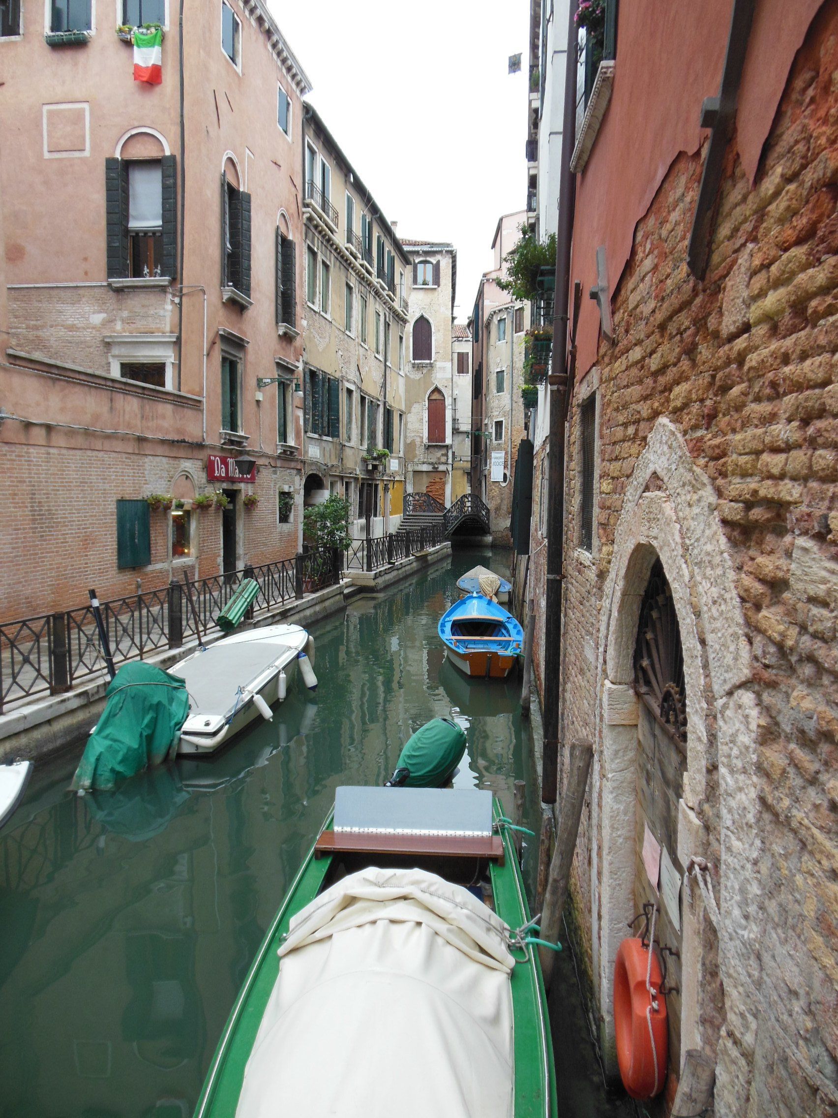 A narrow canal between two buildings with boats in it