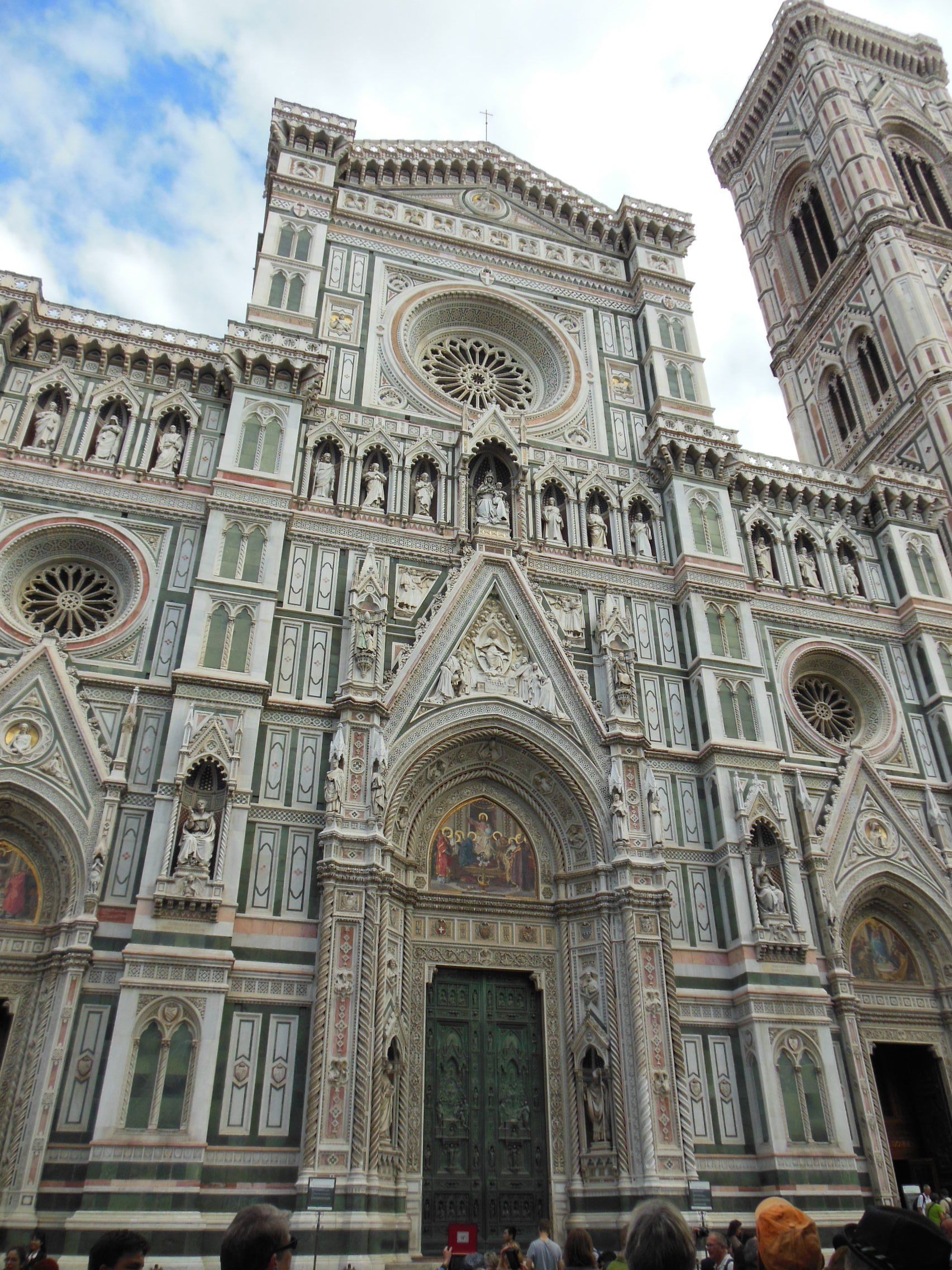 A group of people are standing in front of a large building with a clock tower.