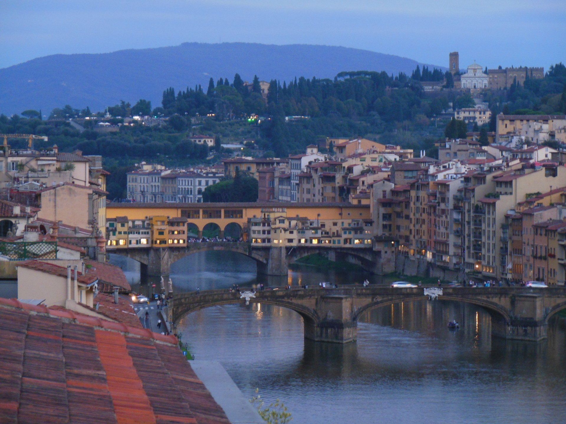 A bridge over a river in a city with mountains in the background
