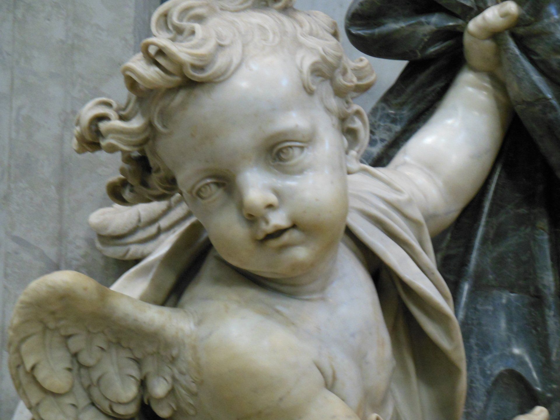 A close up of a statue of a child with wings