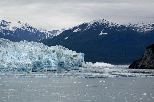 A large iceberg in the middle of a body of water with mountains in the background