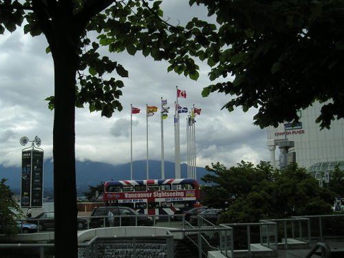 A red double decker bus is surrounded by flags