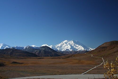 A road going through a desert with mountains in the background.