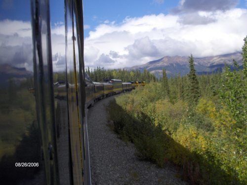 A train is going through a forest with mountains in the background