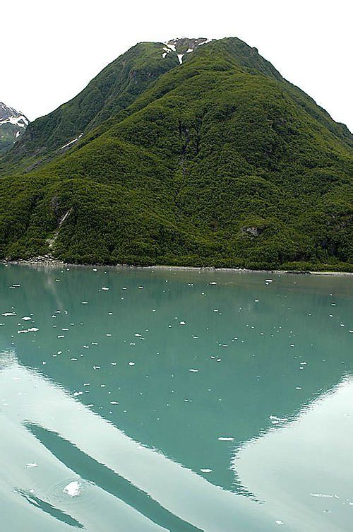 A mountain is reflected in the water of a lake surrounded by trees.