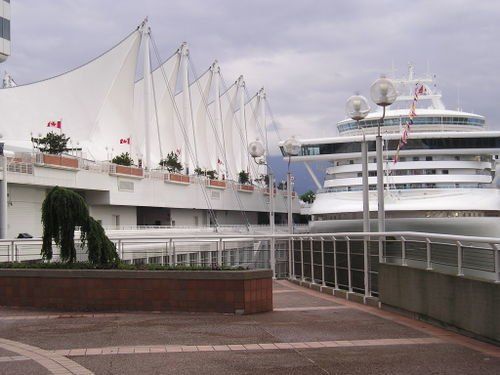 A large cruise ship is docked in front of a large white building