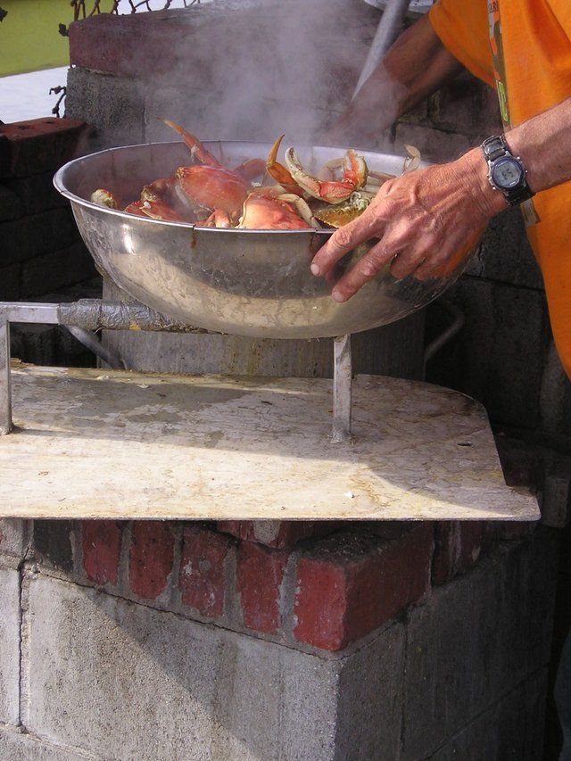 A person is cooking crabs in a metal bowl