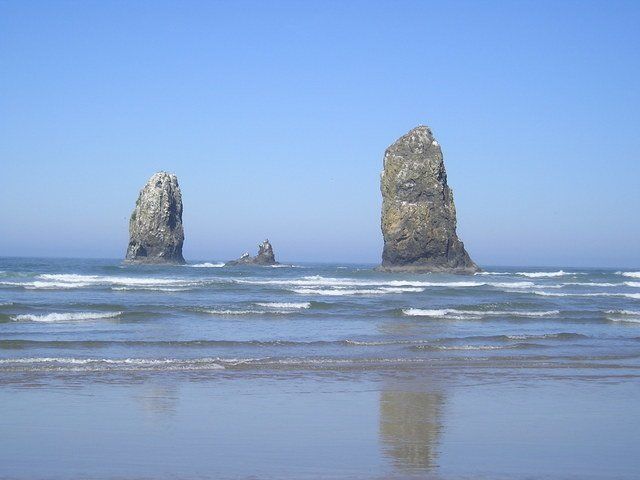 Two large rocks in the middle of the ocean on a beach