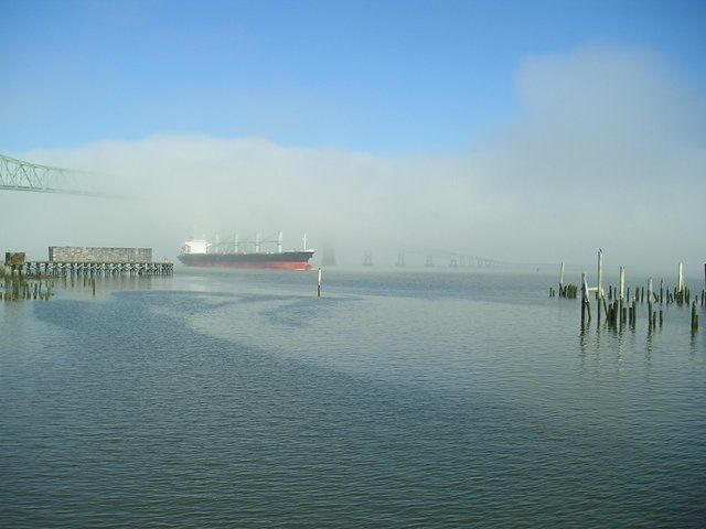 A large ship is in the fog near a dock