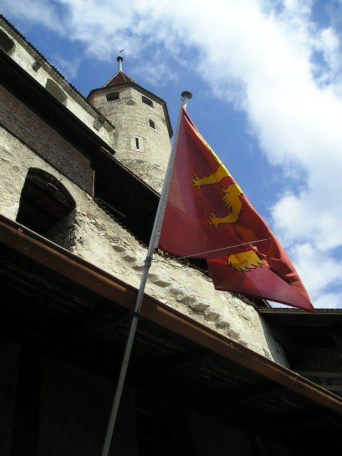 A red and yellow flag is flying in front of a building