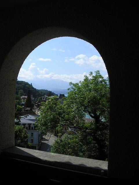 A view of a city through an archway with trees in the foreground