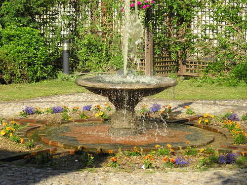 A fountain is surrounded by flowers in a garden.