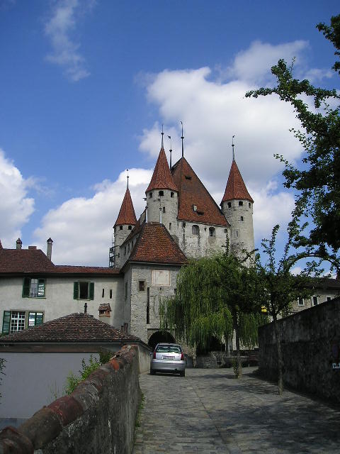 A white car is parked in front of a castle