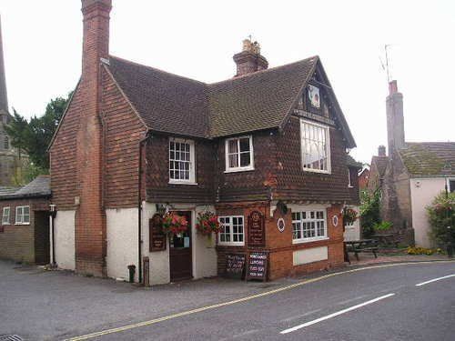 A large brick house is sitting on the corner of a street.