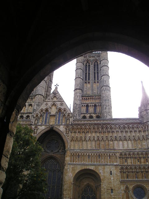A large building with a clock tower is seen through an archway.