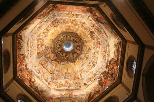 Looking up at the ceiling of a church with a painting on it.