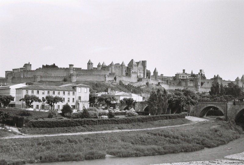 A black and white photo of a city with a bridge in the foreground.