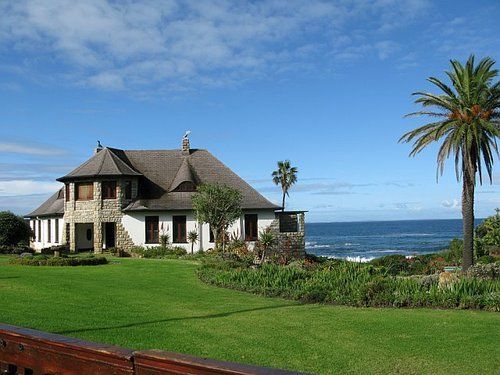 A large house sits on a hill overlooking the ocean