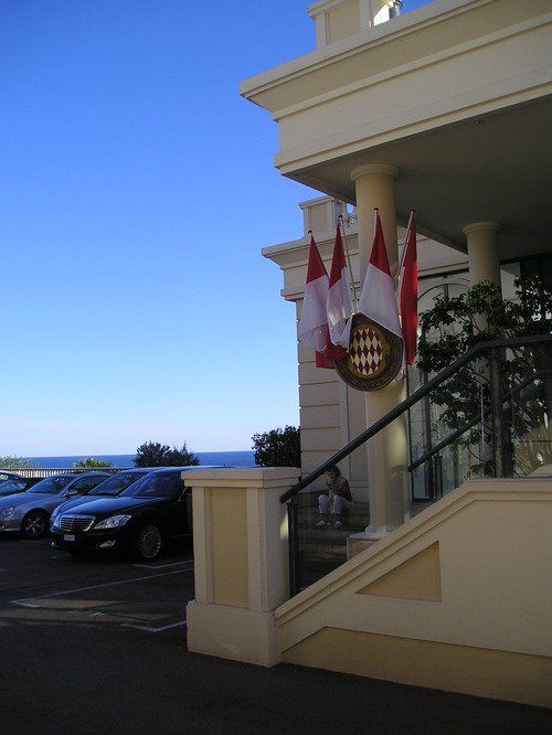 A white building with stairs and flags on the side