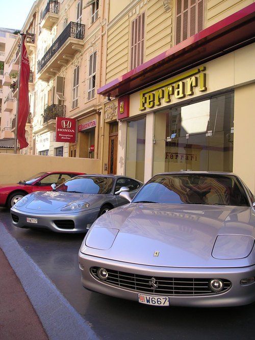 Two ferrari cars are parked in front of a store
