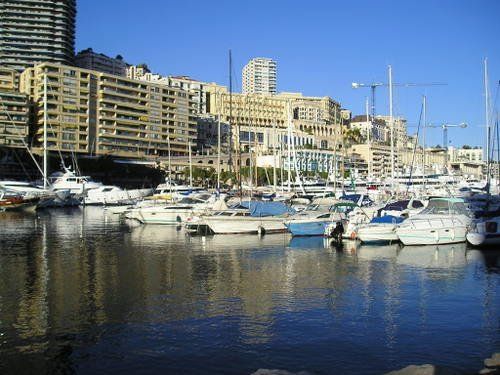 Many boats are docked in a harbor with buildings in the background