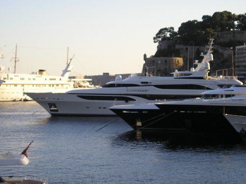 A row of yachts are docked in a harbor and one of them has the word sydney on the side